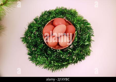 Studiofoto von Ostereiern in einem runden Korb Green Vines auf weißem Hintergrund Draufsicht Stockfoto