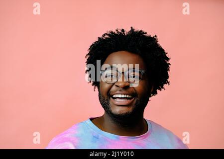 Junger glücklicher afroamerikanischer Mann posiert im Studio auf rosa Hintergrund. Hochwertige Fotos Stockfoto