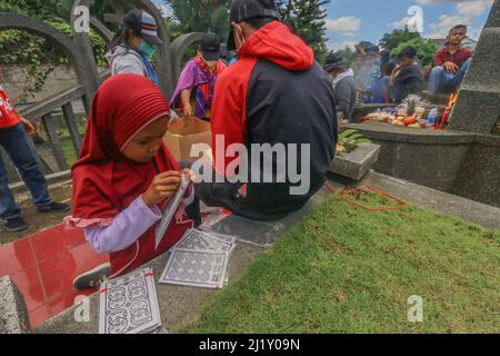 Am 27. März 2021 hilft ein junges Mädchen beim Cheng Beng- oder Qingming-Fest, auch bekannt als Tag der Grabfegen, auf einem chinesischen Friedhof in Bogor, West-Java, Indonesien. Das Qingming Festival oder Cheng Beng ist ein jährliches chinesisches ethnisches Ritual, um sich zu erinnern, zu ehren und nach dem Konfuzianismus zum Ahnengrab zu pilgern. Jeder betet vor den Ahnen, fegt das Grab und betet mit Weihrauch, Geld, Papiergebeten und verschiedenem Zubehör, als Opfergabe an die Ahnen. (Foto von Andi M Ridwan/INA Photo Agency/Sipa USA) Stockfoto