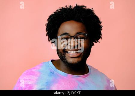 Junger glücklicher afroamerikanischer Mann posiert im Studio auf rosa Hintergrund. Hochwertige Fotos Stockfoto