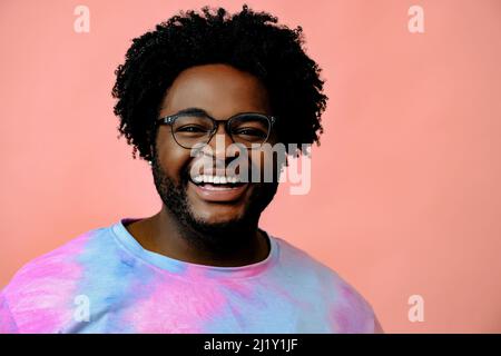 Junger glücklicher afroamerikanischer Mann posiert im Studio auf rosa Hintergrund. Hochwertige Fotos Stockfoto