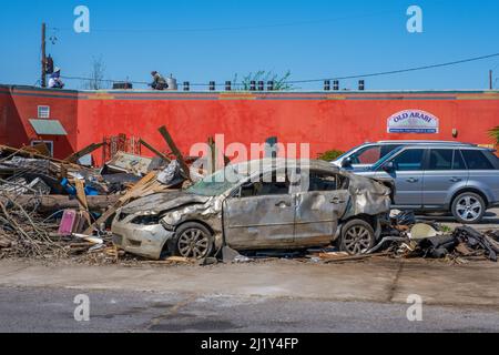 ARABI, LA, USA - 26. MÄRZ 2022: Trümmerhaufen und schwer beschädigte Autos in der Nähe von unbeschädigten Geschäften und geparkten Autos auf der Friscoville Avenue nach dem Tornado Stockfoto