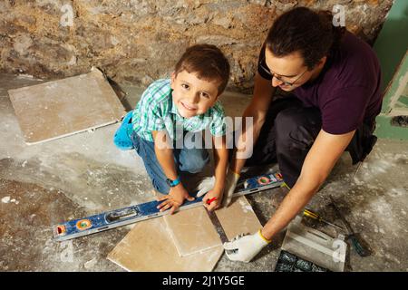 Vater und sein kleiner Junge messen und schneiden Gipskarton Stockfoto