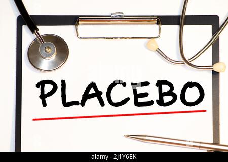 Wörter mit Placebo-Effekt, die auf einem blauen medizinischen Ordner mit Patientenakten, Pillen und Stethoskop auf dem Hintergrund geschrieben sind Stockfoto