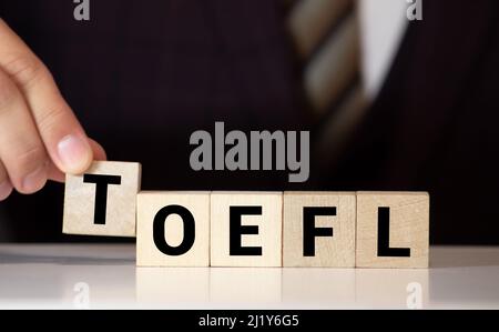 TOEFL - Wörter aus Holzblöcken mit Buchstaben, der Test des Englischen als Fremdsprache, TOEFL-Konzept, weißer Hintergrund. Stockfoto