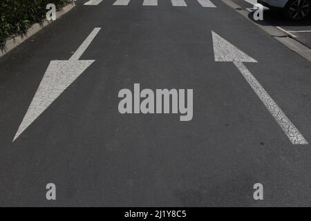 Eine Nahaufnahme von weißer Farbe auf Asphalt zwei Pfeile Stockfoto