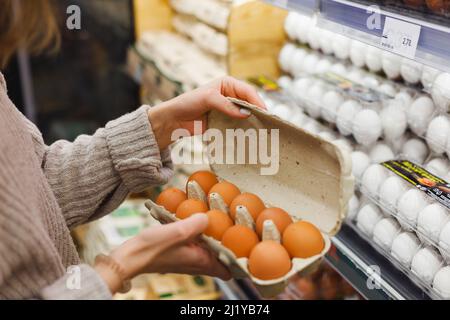 Frau wählt Hühnereier in einem Lebensmittelgeschäft. Nahrungsaufnahme, Ostern Stockfoto