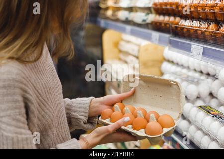 Frau wählt Hühnereier in einem Lebensmittelgeschäft. Nahrungsaufnahme, Ostern. Stockfoto