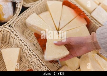 Hand mit einem Stück Käse im Supermarkt Stockfoto