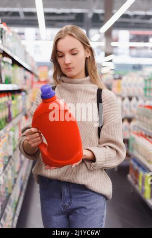 Die junge Frau wählt Waschmittel und Conditioner oder ein Waschgel in einem Geschäft Stockfoto