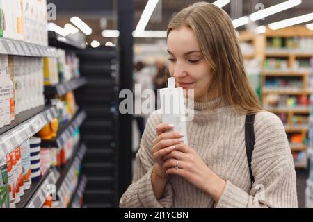 Shopping Kosmetik - Frau riecht Flasche Shampoo im Laden. Stockfoto