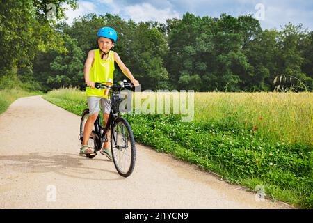 Kleiner Junge sitzen und Fahrrad fahren im Park in der Nähe von Feld Stockfoto