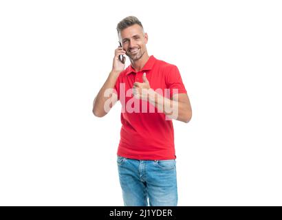 Glücklicher Mann in rotem T-Shirt spricht auf Smartphone isoliert auf weißem Hintergrund. Daumen hoch Stockfoto