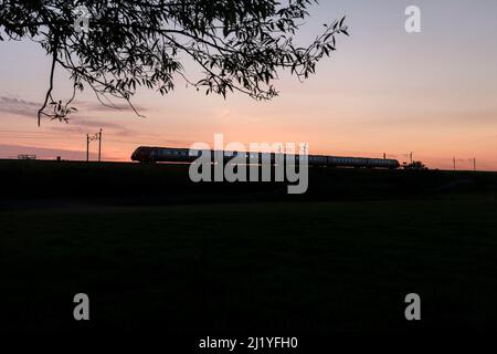 Virgin Trains West Coast 221 Bombardier Diesel voyager-Zug auf der elektrifizierten Hauptlinie der Westküste macht einen Sonnenuntergang Silhouette Stockfoto