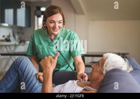 Krankenschwester, die sich während des Hausbesuchs um einen älteren Mann, einen Gesundheitsgast und einen alten Mann kümmert. Eine Krankenschwester oder ein Arzt, der die Gesundheit eines Patienten überprüft, häusliche Pflege Stockfoto