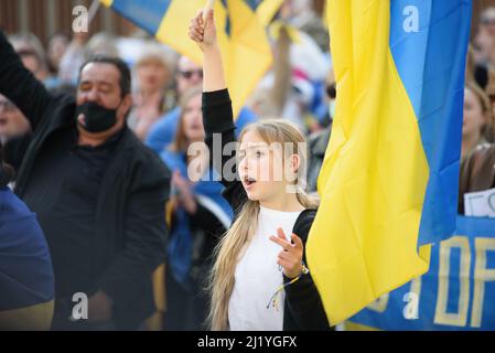 Nikosia, Zypern - 27. März 2022: Junge Protesterin schreit mit ukrainischer Flagge bei einer Kundgebung gegen die russische Invasion in die Ukraine Stockfoto