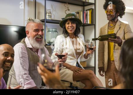 Mehrere Alters- und rassische Gruppe von Freunden feiern etwas, Silvester, Weihnachtszeit, verschiedene Person toasten und Wein zu Hause Party trinken Stockfoto
