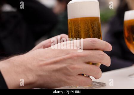 Die Hand des kaukasischen Mannes hält ein Bier im Glas im Freien Stockfoto