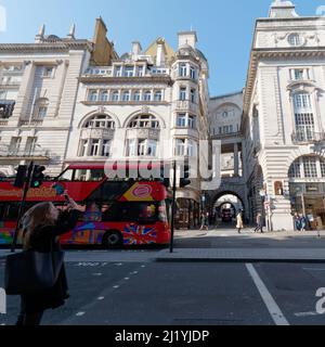 London, Greater London, England, März 08 2022: Tourist macht ein Foto auf der Regent Street mit Blick auf die Air Street, während ein Bus vorbeifährt. Stockfoto