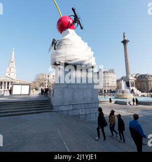 London, Greater London, England, März 08 2022: Touristen blicken auf die Trafalgar Squares Vierter Sockel einer Schlagsahne, Kirsche und Fliegenskulptur. Stockfoto