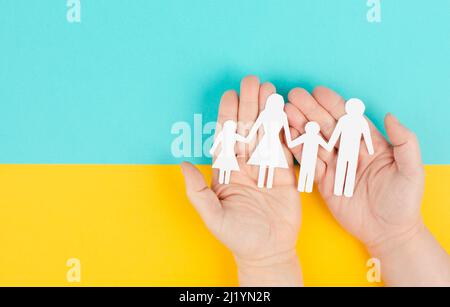 Eltern mit zwei Kindern, die Hände halten, Familienleben, ausgeschnittenes Papier, Kopierraum, gelber und blauer Hintergrund, Beziehung Stockfoto