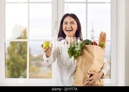 Porträt einer glücklichen jungen Frau mit Papier Lebensmittelbeutel in ihren Händen, in denen frische Bio-Lebensmittel. Stockfoto