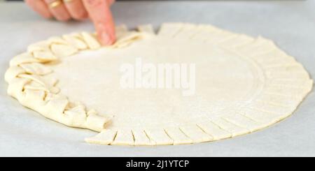 Pizzaherstellung. Draufsicht auf den Pizzateig. Hausgemachte Pizza mit einer geflochtenen Kuchenkruste. Stockfoto