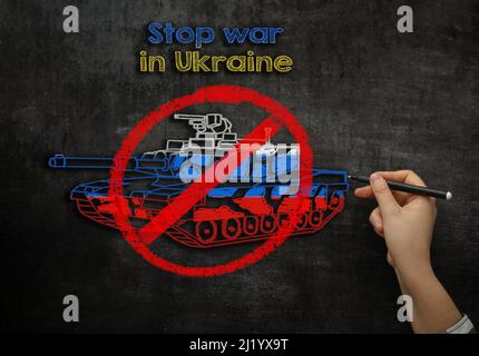 Mädchen zieht einen Panzer auf eine Kreidetafel mit dem Text Stoppen Sie den Krieg in der Ukraine Stockfoto