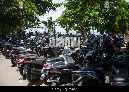 In der Nähe des Strandes von Sanur in Bali parkte man Motorräder und Roller, während ein Mann auf seinem Motorrad saß. Stockfoto