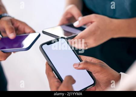 Es geht um die Verbindung. Aufnahme einer Gruppe von Geschäftsleuten, die ihre Smartphones gemeinsam nutzen. Stockfoto