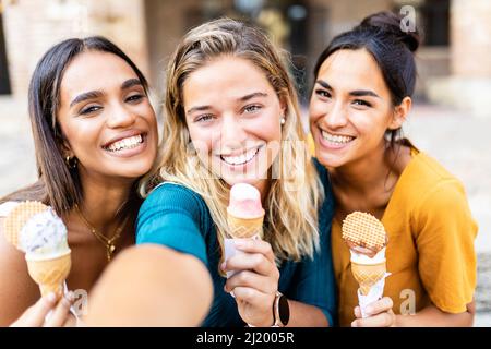 Diverse junge Freundinnen, die zusammen Selfie machen, während sie ein Eis essen Stockfoto