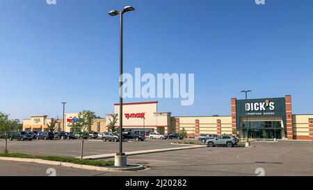 BAXTER, MN - 1 SEP 2021: Einkaufszentrum und Parkplatz mit Autos vor den Geschäften und einem Lichtpfosten, der sich an einem sonnigen Tag in Richtung des blauen Himmels erstreckt Stockfoto