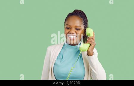 Fröhliche Frau im Gespräch auf Retro-Telefon mit hellgrünen Hörer mit Draht auf Banner Hintergrund. Stockfoto