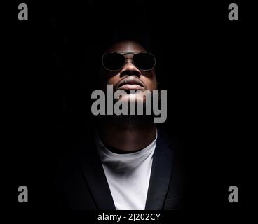 Der Mann, der keine Phantasie hat, hat keine Flügel. Studioaufnahme eines Mannes, der eine Sonnenbrille trägt, während er vor einem dunklen Hintergrund posiert. Stockfoto