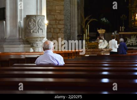 Der ältere Mann betet in einer Kirche Stockfoto