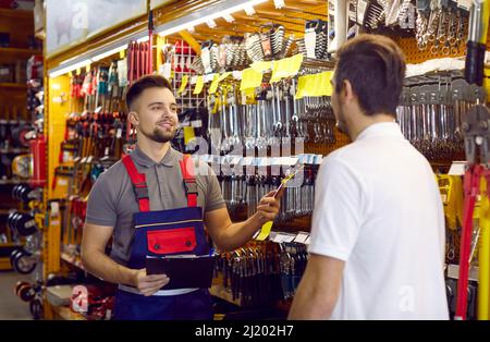 Verkaufsassistent im Baumarkt hilft Kunden bei der Auswahl von Werkzeugen für Reparaturen zu Hause Stockfoto