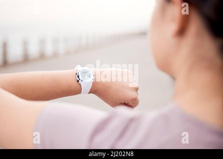 Zeit ist kostbar, nutzen Sie sie intelligent. Aufnahme einer nicht erkennbaren Frau, die während ihres Laufs auf der Promenade eine intelligente Uhr benutzte. Stockfoto