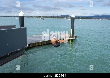 Tauranga Neuseeland März 26 2022;Teenager springt von Plattform int Wasser unten. Stockfoto