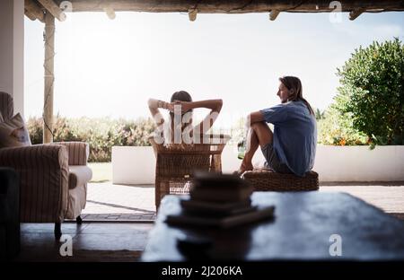 Es gibt nichts Besseres, als den ganzen Tag mit Ihnen zu chillen. Rückansicht eines jungen Paares, das draußen auf der Veranda zu Hause chillt. Stockfoto