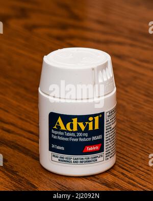 Eine weiße Plastikflasche mit 24 beschichteten Tabletten von Advil, 200 mg Ibuprofen, einem Schmerzmittel und Fieberreduzierer NSAID, isoliert auf einem Eichenschreibtisch Stockfoto