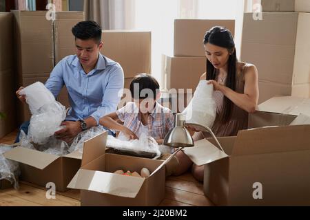 Zusammenarbeit als Familie am Umzugstag. Aufnahme einer Familie, die beim Umzug Boxen packte. Stockfoto