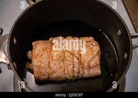 Nahaufnahme, selektive Konzentration auf einen saftigen Schweinekastall in einem großen Topf mit Sojasauce und grünen Zwiebeln Stockfoto