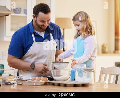 Sie macht mich so stolz. Schuss eines Vaters, der seiner Tochter dabei half, Mehl in eine Schüssel zu sieben. Stockfoto