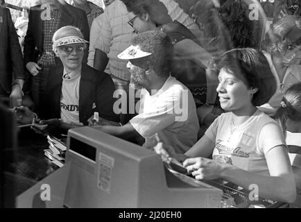 Eine Veranstaltung, die im Hollywood Outlet als „Amos und Andy“ für die berühmten Amos Cookies, Andy Warhol und Wally Amos bezeichnet wird, signiert Bücher neben einer Kasse. Los Angeles, Kalifornien, 1979. Stockfoto