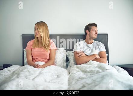 Im gleichen Bett, aber Welten auseinander. Aufnahme eines jungen Paares, das sich im Bett ignorierte. Stockfoto