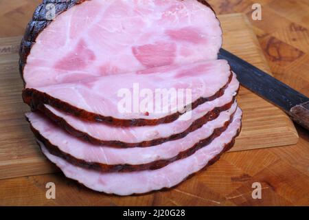 Nahaufnahme eines in Scheiben geschnittenen Schinken auf dem Schneidbrett Stockfoto