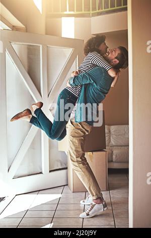 Wir haben es gemacht, Baby. Aufnahme eines glücklichen jungen Paares, das sich umarmt, als sie in ihr neues Zuhause ziehen. Stockfoto