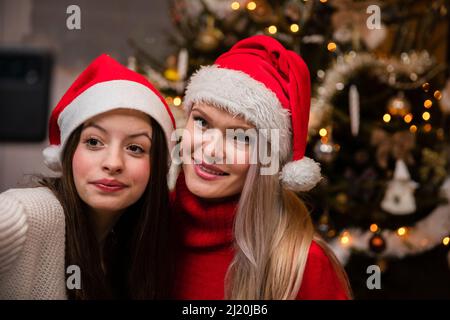 Mutter und Tochter machen ein Selfie, nachdem sie den Weihnachtsbaum dekoriert haben. Stockfoto