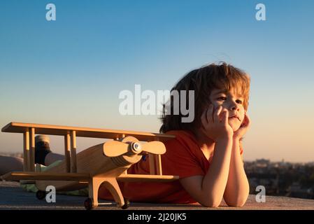 Glückliches Kind spielt mit Spielzeug Flugzeug vor blauem Himmel Hintergrund. Nettes Kind 8 Jahre alt an einem sonnigen Sommertag. Kinder träumen vom Reisen. Stockfoto