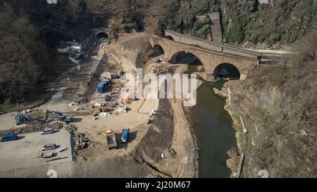 Altenahr, Deutschland. 25. März 2022. Vor dem Tunnel in Altenahr laufen die Bauarbeiten an der Rotweinstraße, die durch das Ahrtal verläuft (Luftaufnahme mit Drohne), in vollem Gange. Die Überschwemmung im Juli 2021 hat die landschaftlich reizvolle Route (B 267) bei Altenahr neben einem Tunnel komplett weggefegt. (Nach dpa: Rotweinstraße im Ahr-Hochwassergebiet nur im Sommer befahrbar). Quelle: Thomas Frey/dpa/Alamy Live News Stockfoto